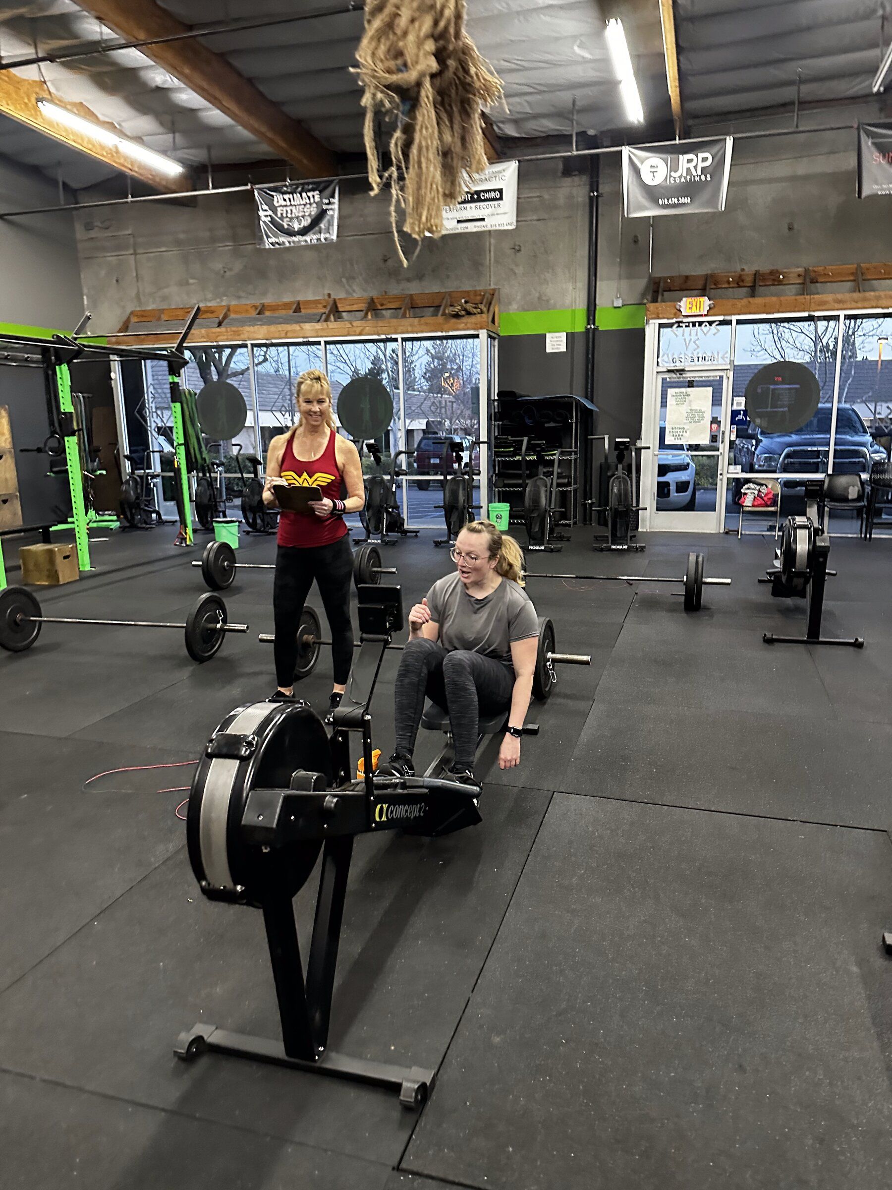 A coach times a member rowing on the gym floor at El Dorado Hills CrossFit